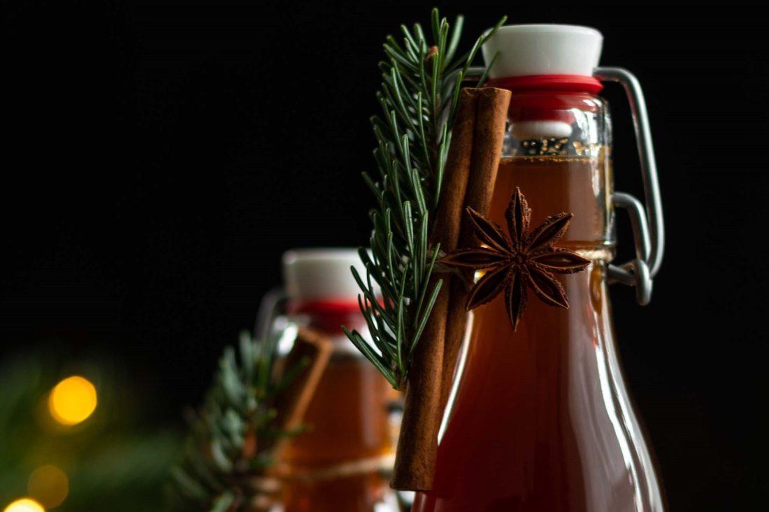 Lebkuchensirup in Flaschen weihnachtlich dekoriert mit einer Zimtstange, Sternanis und einem Tannenzweig.