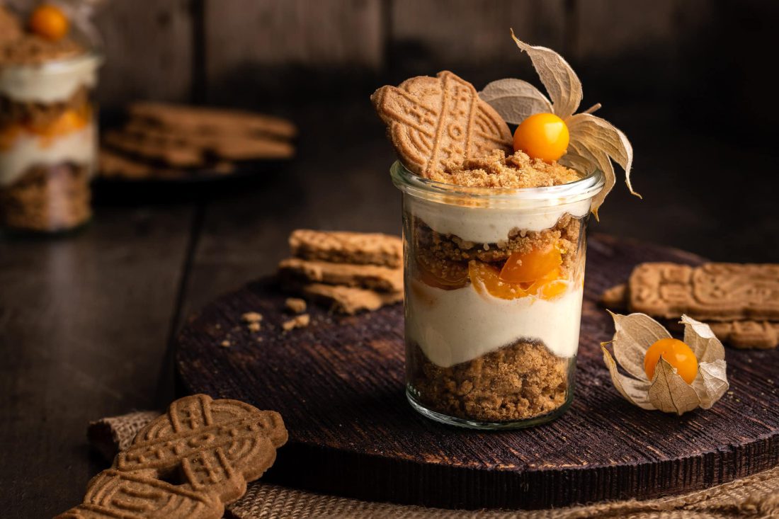 Ein Mascarpone Spekulatius-Dessert im Glas garniert mit einem Spekulatiuskeks und frischer Physalis.