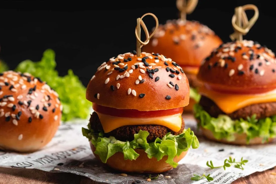 Mini Burger belegt mit frischem Gemüse und jeweils einem Patty als Fingerfood.