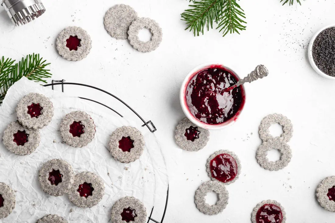 Die saftigen Mohnplätzchen werden mit einer roten Marmelade gefüllt.