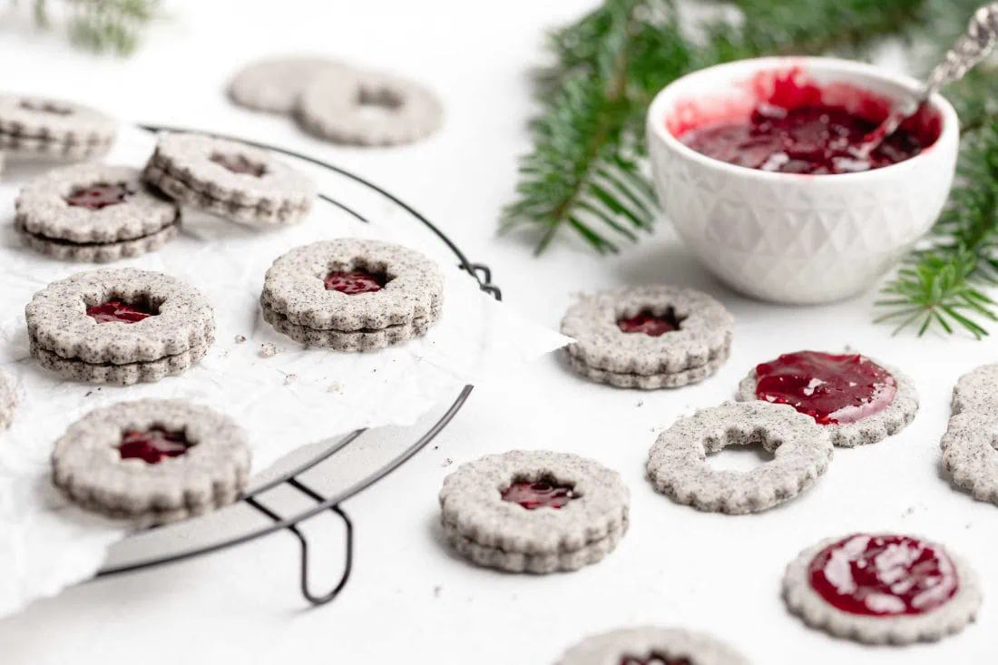 Mit Marmelade gefüllte Plätzchen mit Mohn liegen auf einem Gitter.