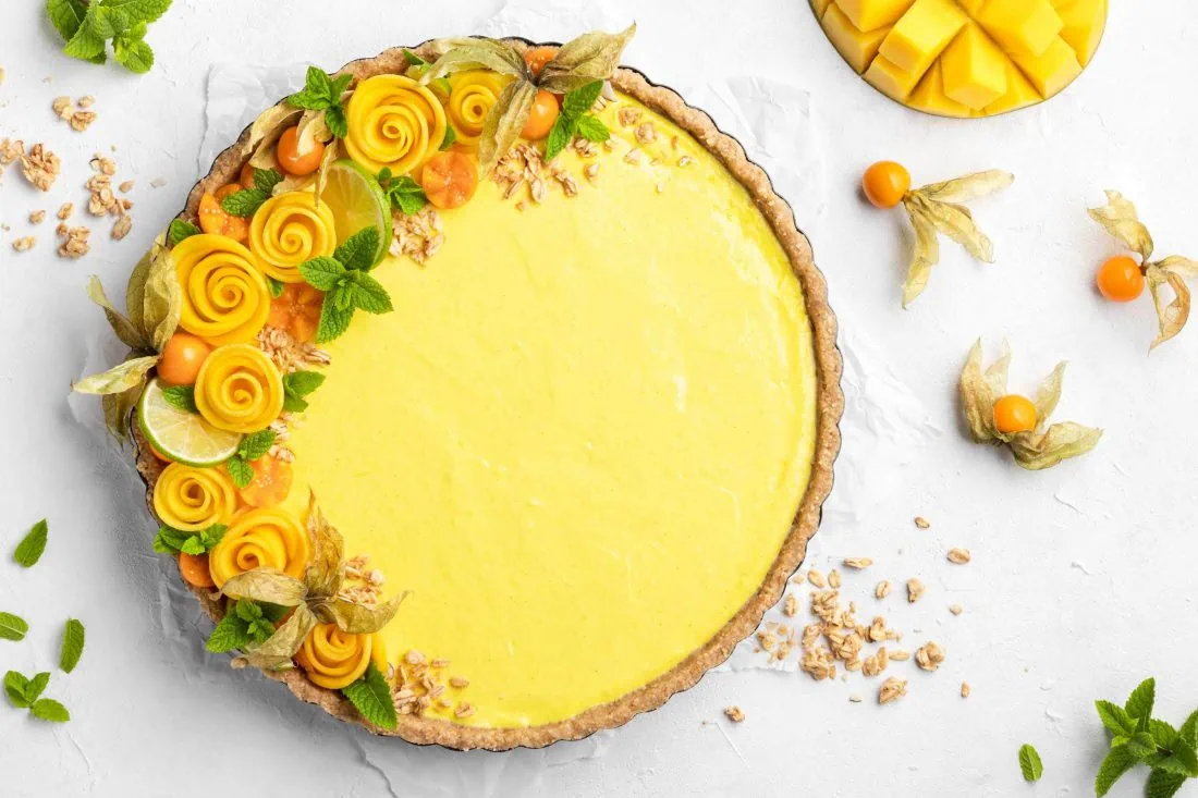 Mango Tarte ohne Backen sommerlich dekoriert mit Mango, Minze, Physalis und Granola.