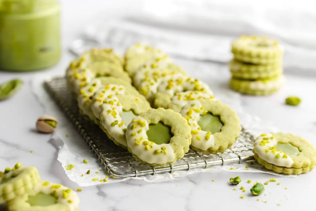 Grüne Weihnachtsplätzchen mit Pistazien und weißter Schokolade auf einem Gitter.