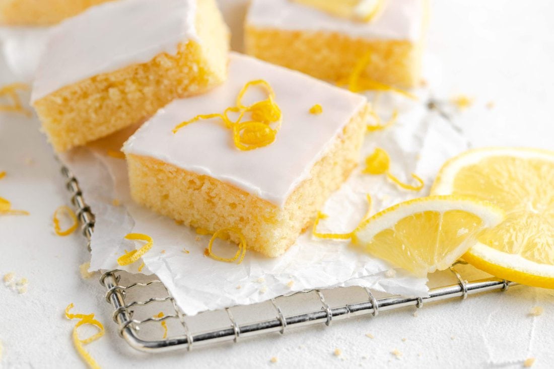 Saftiger Zitronen-Buttermilchkuchen in quadratische Stücke geschnitten auf einem Kuchengitter.