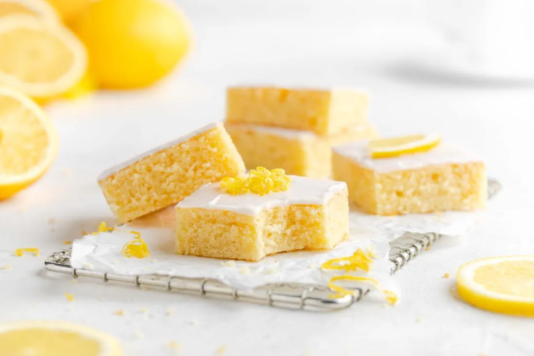 Mehrere Stücke eines Zitronen-Buttermilchkuchen auf einem Gitter. Von einem Stück wurde bereits abgebissen.