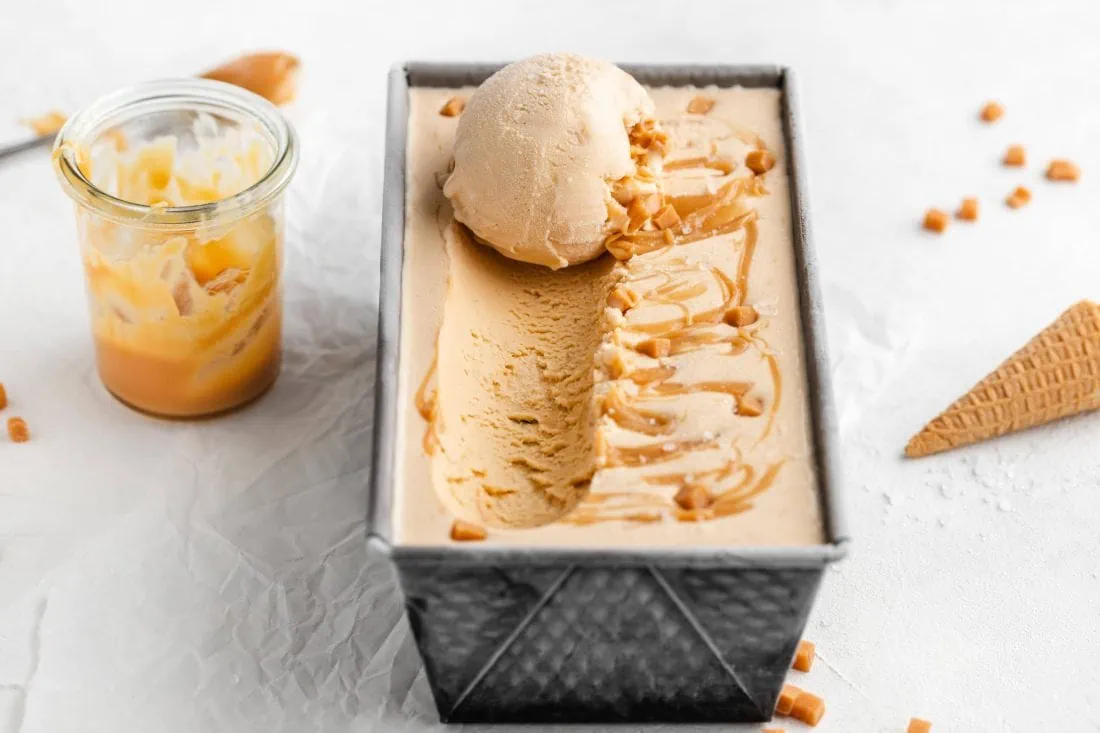 Gesalzenes Karamelleis in einer Form. Neben dem Eis steht die Salted Caramel Sauce aus dem Rezept.