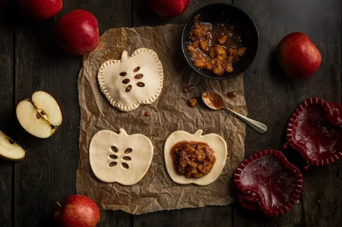 Bild der Zubereitung der Apfeltaschen: In Apfelform ausgestochener Blätterteig wird mit einer Apfelfüllung mit Zimt gefüllt.