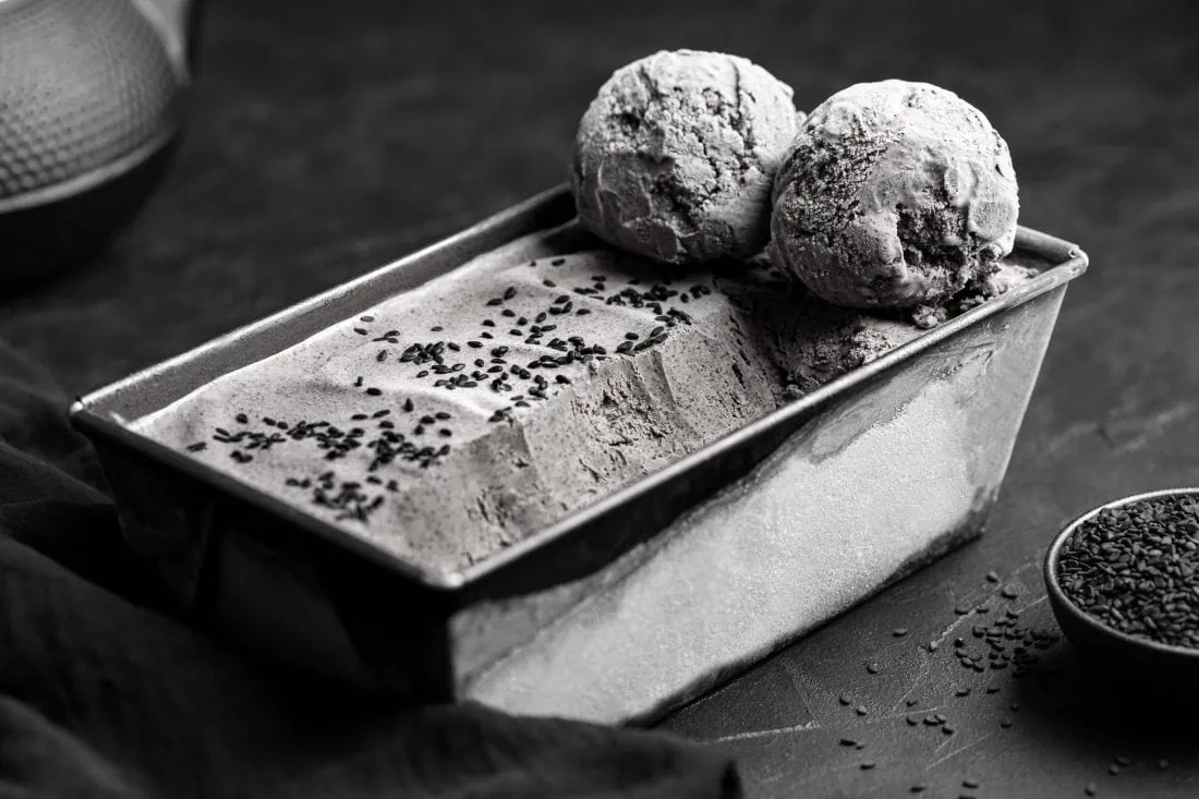 Zwei Kugeln schwarzes Sesameis liegen auf der Form in die die restliche Eiscreme abgefüllt wurde.