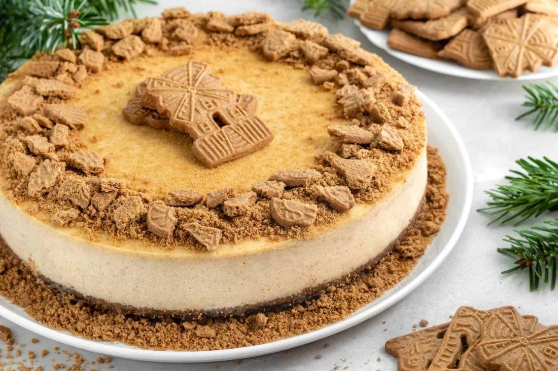 Spekulatius Cheesecake garniert mit Spekulatiusbröseln auf einer weißen Kuchenplatte.