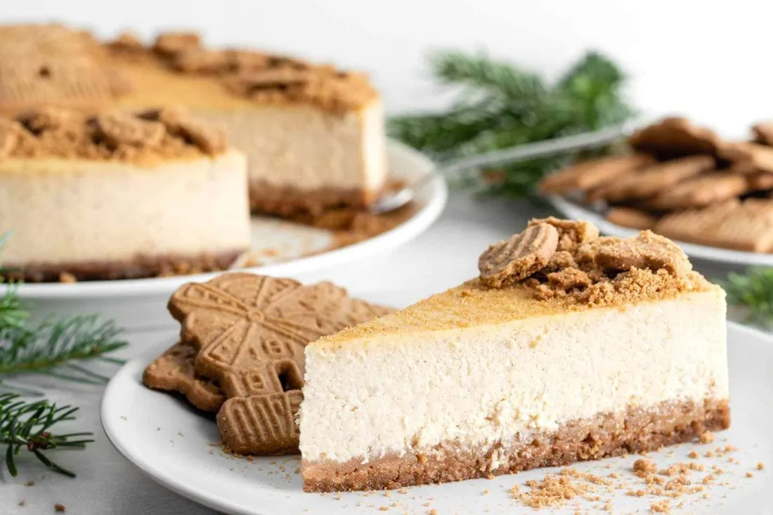 Spekulatius Cheesecake Stück auf einem Teller bestreut mit Spekulatiuskeksen.