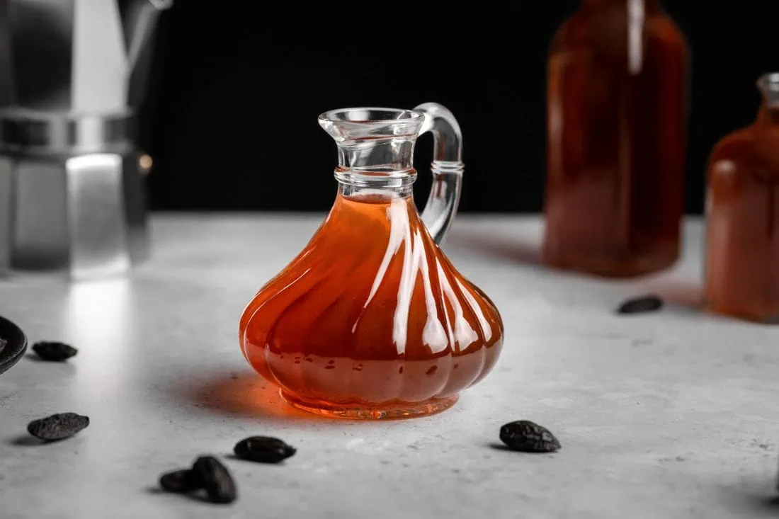 Eine Flasche gefüllt mit einem selbstgemachten Tonkabohnensirup zum Verfeinern von Heißgetränken und Desserts.