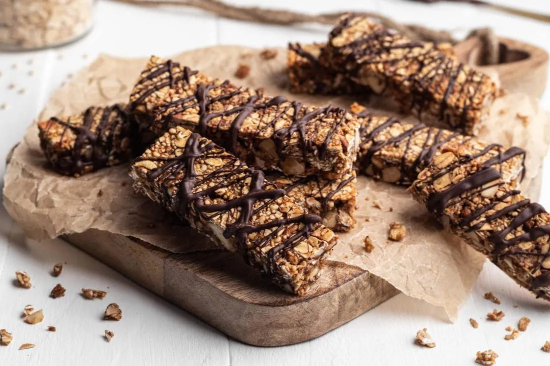 Vegane Schoko-Bananen Müsliriegel ohne raffinierten Zucker liegen übereinander gestapelt auf einem Backpapier.
