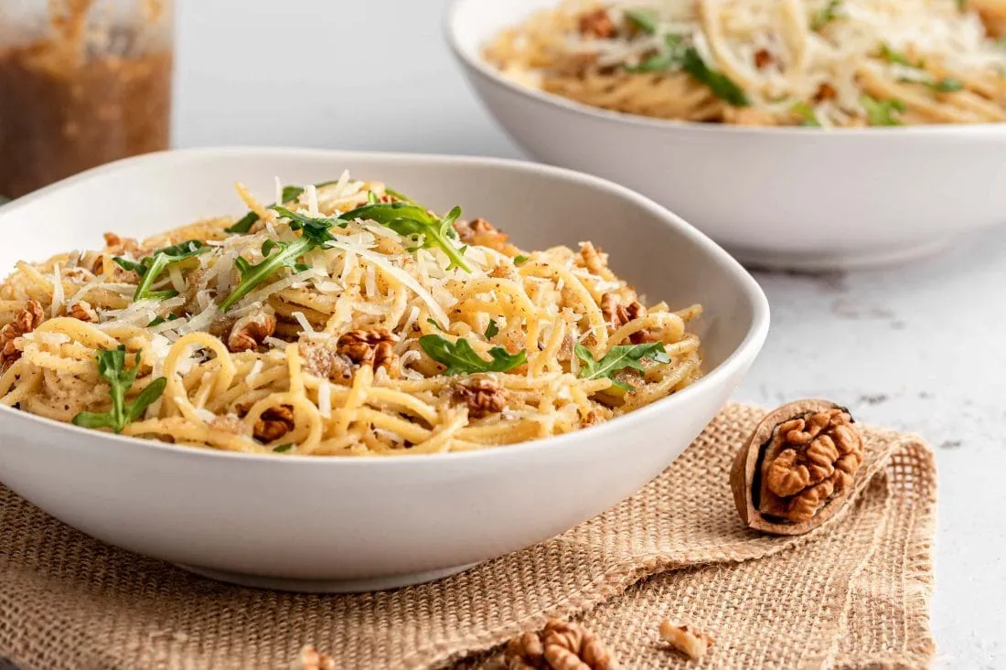 Zwei tiefe Teller gefüllt mit Nudeln mit italienischem Walnusspesto und Parmesan.