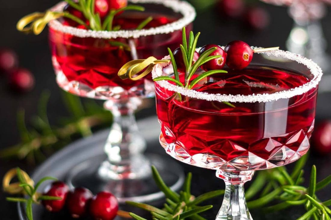 Wodka Cranberry Cocktails mit Rosmarin als Aperitif garniert mit einem Zuckerrand.