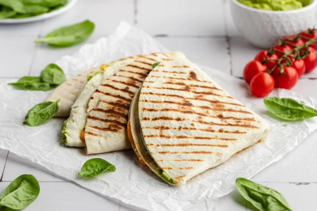 Gebratene und gefaltete Wraps mit Guacamole, Käse und Gemüse gefüllt.
