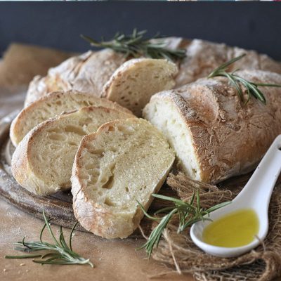 Brot mit Olivenöl und Rosmarin auf Tisch. Verlinkt auf Brot-Rezepte.