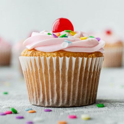 Cupcake mit rosa Glasur und bunten Zuckerstreuseln. Verlinkt auf Rezepte aus der Kuchentheke.